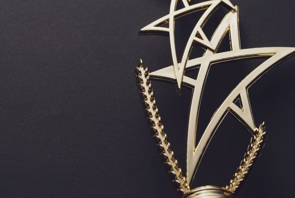 Golden trophy with pedestal in shape of triple star on black background